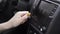 The driver adjusting the volume of a radio inside a car. Action. Close up of a woman hand with yellow manicure turning