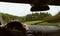Driver driving a modern off road left hand drive LHD car on the mountain green forest country road at rainy moody day. POV inside