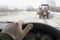 Driver hand behind the wheel of a car that drives behind two slow moving tractors