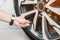 Driver hand inflating tires of vehicle, removing tire valve nitrogen cap for checking air pressure and filling air on car wheel at