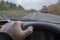 Driver hand on the steering wheel of a car passing on the road being repaired