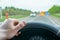 Driver hand on the steering wheel inside the car on the background of the highway