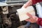 Driver hands inserting air filter paper cartridge inside plastic airbox of car engine, close up view