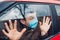 Driver man sitting in car wearing protective mask scared of sick flu coronavirus people outside. People panic. Pandemic