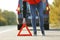 Driver putting warning triangle on asphalt road