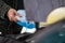 Driver refilling the blue non-freezing windshield washer liquid in the tank of the car, close-up