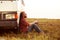 Driver resting in a field near his car