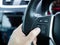 Driver`s hands press volume button on a steering wheel