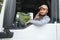 A driver sitting inside the semi-truck while looking through the open window with multiple trucks parked in the