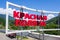 Driveway sign of Krasnaya Polyana ski mountain resort at summer. Road stele with resort`s livery on scenic green forest and