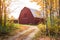 Driveway to a red wooden barn in the countryside of New England on a sunny autumn day