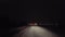 Driving Approaching City Traffic Lights While Snowing on Rural Road at Night.  Driver Point of View POV Moving Toward Urban