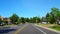 Driving approaching stop sign on residential city road with lush trees during summer day. Driver point of view pov