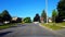 Driving Around a Bend of Residential City Road With Lush Trees During Summer Day.  Driver Point of View POV Turning