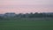 Driving in a car through the rural fields outside the city at sunset. Pink sunset landscape sky in the background