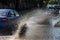 Driving cars on a flooded road during floods caused by rain storms. Cars float on water, flooding streets. Splash on the machine.