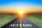 Driving on an empty asphalt road towards the setting sun and sign which symbolizing success.