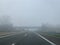 Driving on a empty highway in thick fog.