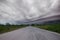 Driving on an empty road. Empty asphalt road through the green field and clouds on rainstorm in rainy season. Open road ahead, end