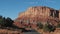 Driving On An Empty Road Leading To Red Mountain Rocks Buttes In Desert Valley