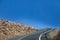 Driving mountain road into a hairpin curve with drop-off to one side and just the sky showing up above the tree line on Pikes Peak