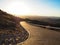 Driving offroad car on adventure road trip through proper block paved curved road among dried desert and rock mountain landscape