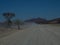 Driving offroad vehicle through dusty unpaved road among desert