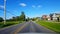 Driving Residential City Road With Lush Trees During Summer Day.  Driver Point of View POV Along Beautiful Sunny Street.