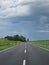 Driving on a streight road, cloudy sky and green surroundings