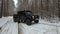 Driving SUV 6x6 by the off-road in the winter forest, front view right