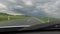Driving towards black cloudy clouds on the road outside the settlements filmed from inside the car.