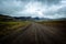 Driving on an unpaved road in summer in Iceland, moutains landscape moody sky with dark clouds