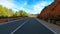 Driving vehicle on a long asphalt straight road in the nature with blue sky and horizon in background. Concept of travel and