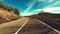 Driving vehicle on a long asphalt straight road in the nature with blue sky and horizon in background. Concept of travel and