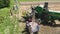 Drohobych, Ukraine - 04 July, 2018: Aerial view of combine harvester winnowing wheat into big bag held by people. Harvesting