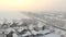 Drone 4K aerial footage of village in the plain covered with snow. White cloudy winter weather