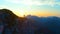 DRONE: Adventurous male hiker is illuminated by the golden summer sunrise.