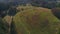 Drone aerial circle view of green open pasture between woods