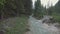 Drone aerial flying over a wild mountain river with woman on the bridge in Dolomites Alps