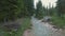 Drone aerial flying over a wild mountain river with woman on the bridge in Dolomites Alps