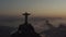 Drone, aerial shot of Christ the Redeemer silhouette above clouds of Rio de Janeiro during summer sunrise