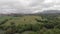 Drone aerial view above hills and forests and large green meadows