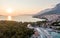 Drone aerial view of Makarska city, Croatia. Sunset over the city, beach and se. Biokovo mountains in the background. Summer time