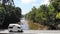 Drone aerial vision of a camper van passing through a bridge in tropical forest