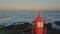 Drone amazing evening lighthouse under pink skyline. Ocean waves rolling coast