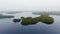 Drone approaching small islands with dense forest in a lake with foggy horizon. Willard Lake, Ontario, Canada