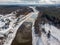 Drone areal view of river Venta flowing near forest on a cold snowy winter day