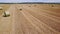 Drone backward flight over field with hay bales.