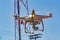 Drone with camera flying with antenna , pole, electricity wires and blue sky in the background