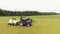 Drone camera shows big colorful equipped tractors standing on big green field.